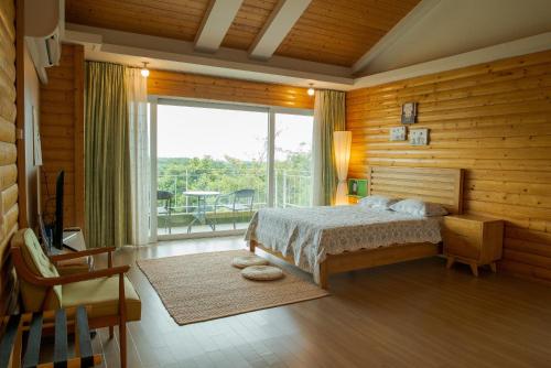 a bedroom with a bed and a large window at Green Narae Pension in Seogwipo