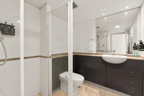 a white bathroom with a toilet and a sink at City Skyline Views CBD Apartment - 1602 in Sydney