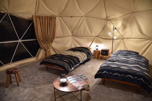 a room with two beds in a tent at Tokachi Nakasatsunai Glamping Resort Feriendorf in Naka-satsunai