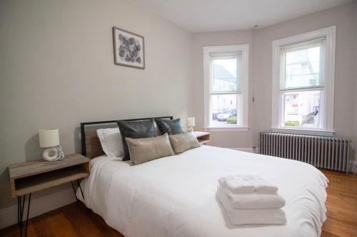 1 dormitorio con 1 cama blanca grande y 2 ventanas en 2 bedroom condo close to Boston and Cambridge with free parkings en Boston