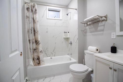 baño blanco con bañera, aseo y lavamanos en 2 bedroom condo close to Boston and Cambridge with free parkings en Boston