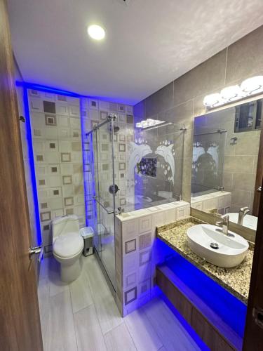 a bathroom with a toilet and a sink with blue lights at Finca La Perla in Armenia