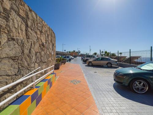 a parking lot with cars parked next to a stone wall at Incredible Sunsets in Puerto Rico de Gran Canaria