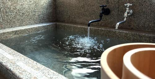a bath tub with a water fountain at EXP Co Onsen 呼隱撰 in Atami