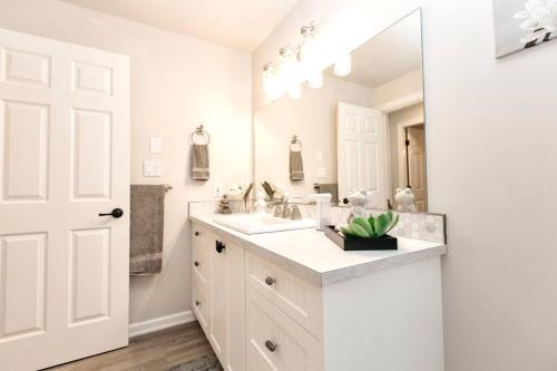Baño blanco con lavabo y espejo en Gorgeous 2 Bedroom Cottage by the City en Victoria
