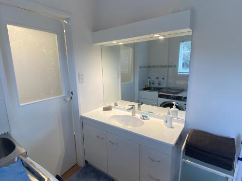 uma casa de banho com um lavatório e um espelho em Delight at Golf em Auckland