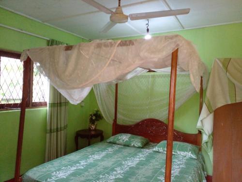 a bedroom with a canopy bed with green walls at Pradeepa house in Unawatuna