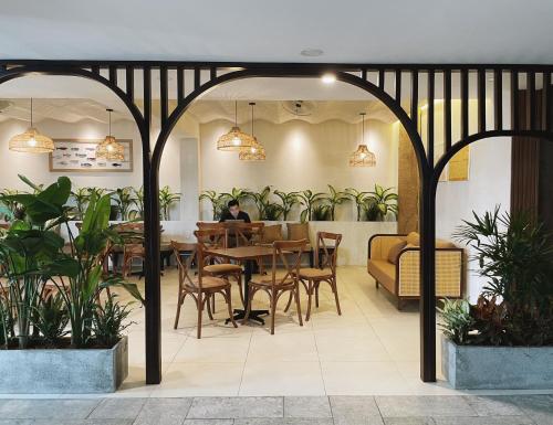 a restaurant with a table and chairs and plants at Phuong Nam Hotel An Giang in Long Xuyên