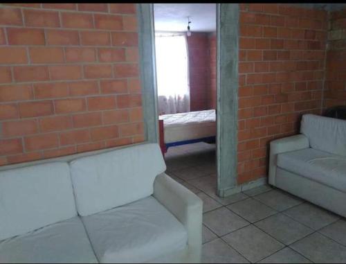 メキシコシティにあるDepartamento, Zona de hospitalesの白いソファ2台とレンガの壁が備わる客室です。