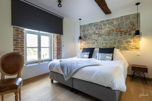a bedroom with a large bed and a brick wall at la chocolaterie in Roly