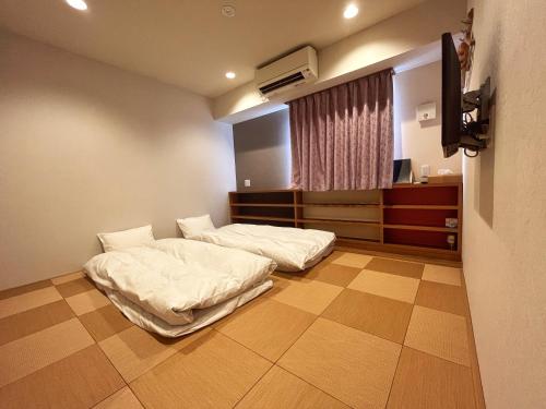a hospital room with two beds and a television at Kansai Seaside Hotel in Kaizuka