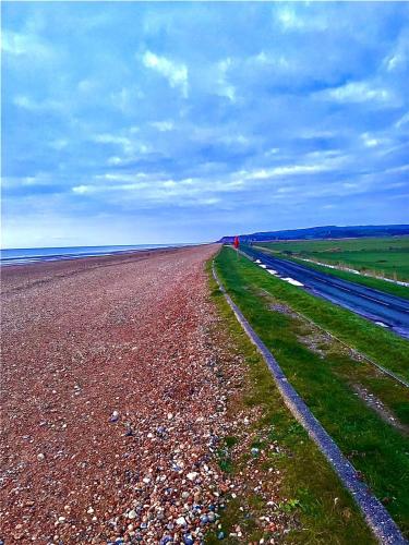 a long dirt road next to a field of grass at Seascape Horizon at Camber Sands in Camber