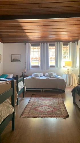 a bedroom with a large bed and two windows at Casa do Fachoalto in Petrópolis