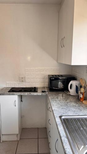 eine Küche mit weißen Schränken und einer Arbeitsplatte in der Unterkunft S-star luxury Lounge in Roodepoort
