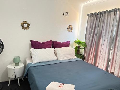 ein Schlafzimmer mit einem blauen Bett mit lila und weißen Kissen in der Unterkunft S-star luxury Lounge in Roodepoort