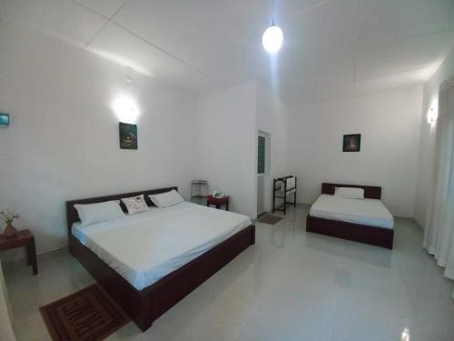 a bedroom with two beds in a white room at S & D Resort in Anuradhapura
