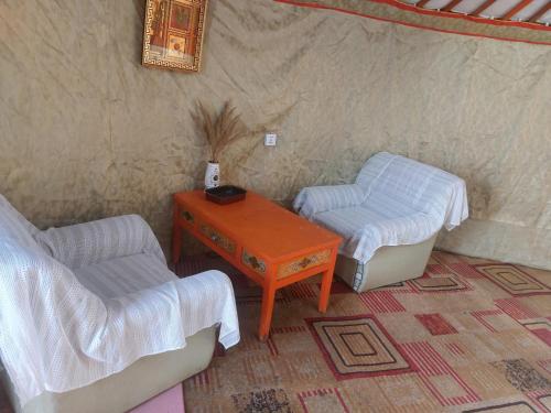 a room with two beds and a table and a chair at Gana's Guest House and Tours in Ulaanbaatar