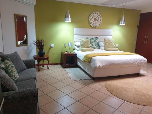 a bedroom with a bed and a chair and a couch at Damicha Boutique Lodge in Ezulwini