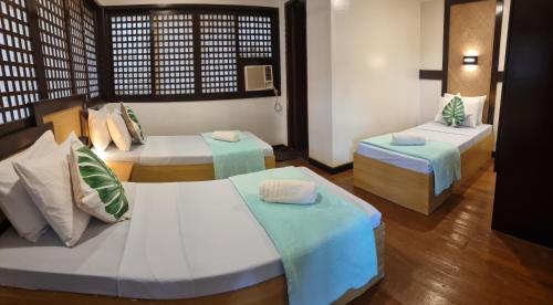 a room with two beds and two tables at Aquaventure Reef Club in Mabini