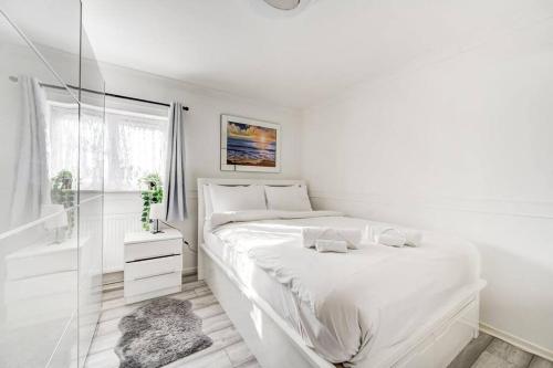 a white bedroom with a large bed and a window at GuestReady - Urban Comfort Near Wembley Stadium in London