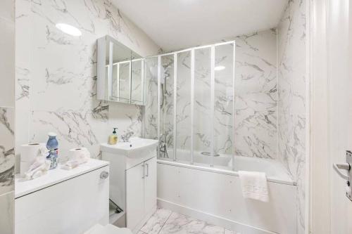 a white bathroom with a tub and a sink at GuestReady - Urban Comfort Near Wembley Stadium in London