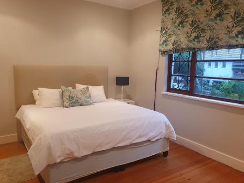 ein Schlafzimmer mit einem weißen Bett und einem Fenster in der Unterkunft Northlands Manor in Durban