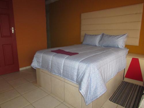 um quarto com uma cama grande e um cobertor azul em Cozy Queen-Bed Apartment in Hammanskraal 