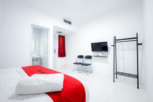 a bedroom with a red and white bed and a tv at RedDoorz near Jalan Cikini in Jakarta