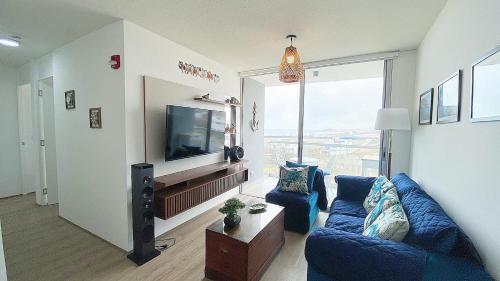 a living room with a blue couch and a tv at Depa playa San Bartolo 3 camas piscina wifi juegos in Lima