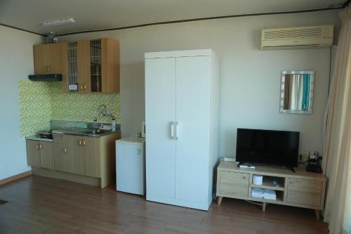 una cucina con frigorifero bianco e TV di Mangsang Beach Pension a Gangneung