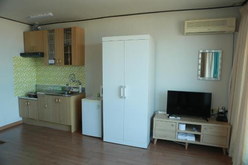 a kitchen with a white refrigerator and a tv at Mangsang Beach Pension in Gangneung