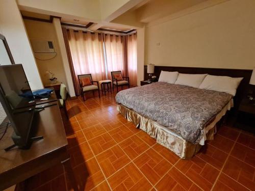 a hotel room with a bed and a television at Luxury 1 BR Suite Malarayat Lipa in Lipa