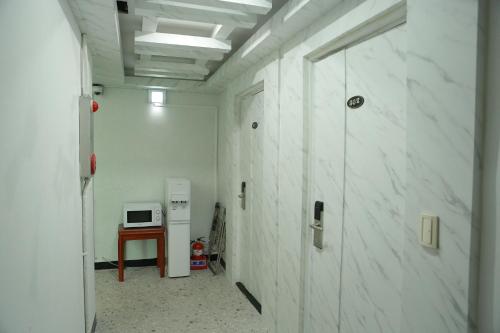 a hallway with white marble walls and a microwave at Mangsang Beach Pension in Gangneung