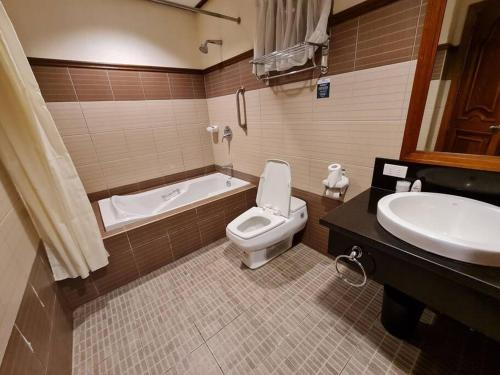 ein Badezimmer mit einer Badewanne, einem WC und einem Waschbecken in der Unterkunft Luxury 1 BR Suite Malarayat Lipa in Lipa