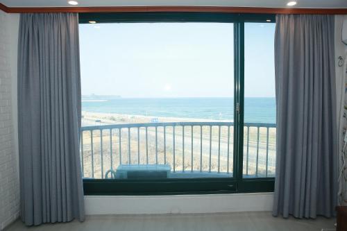 a room with a large window with a view of the ocean at Mangsang Beach Pension in Gangneung