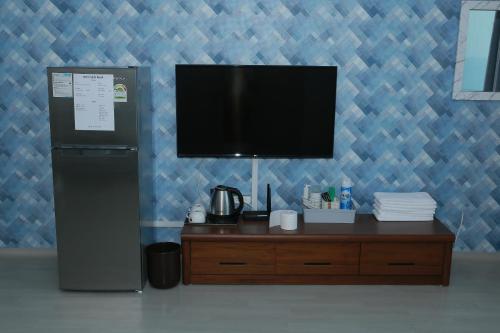 a television on a blue wall with a wooden dresser at Mangsang Beach Pension in Gangneung