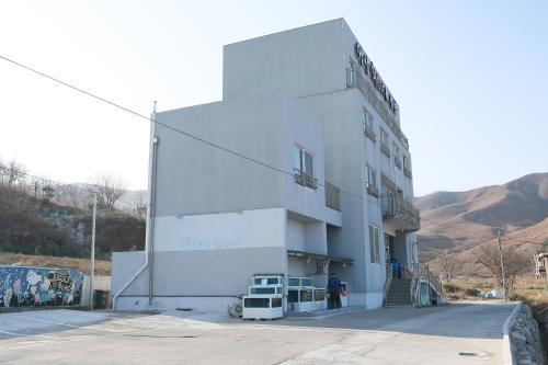 a white building with a person standing in front of it at Mangsang Beach Pension in Gangneung