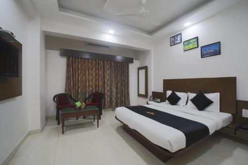 a hotel room with a large bed and a chair at Saish Hotel Shirdi in Shirdi