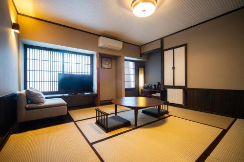 a living room with a coffee table and a tv at Yasuraginoyado Yufu in Beppu
