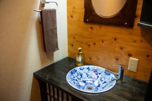 lavabo en el baño con un tazón azul y blanco en Yasuraginoyado Yufu en Beppu