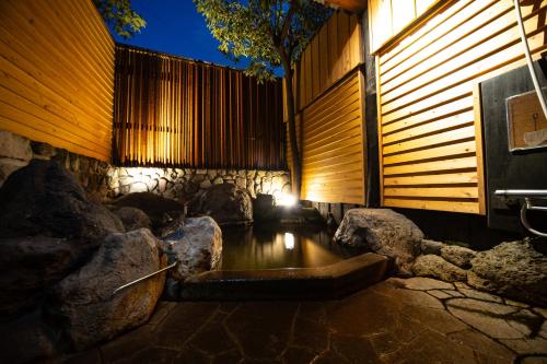 a bathtub in a room with rocks and a fence at Yasuraginoyado Yufu in Beppu