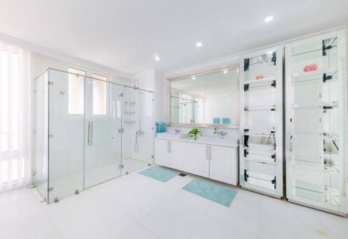 a white bathroom with a shower and a sink at Pristine Paradise Villa In Palm Jumeirah in Dubai