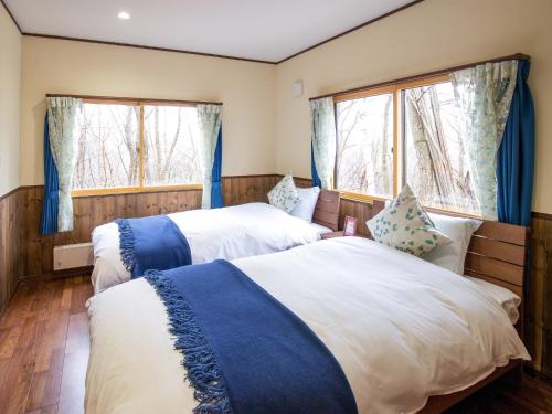 two beds in a room with two windows at KuDo's Lodge - Vacation STAY 85093 in Chikuni