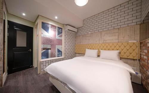 a bedroom with a large white bed and a black door at B-Bas Hotel in Daegu