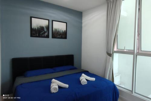 Un dormitorio con una cama azul con toallas blancas. en Leisure homestay@Sutera Avenue 2-1007, en Kota Kinabalu