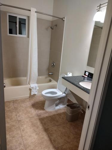 a bathroom with a toilet and a sink and a tub at Economy Inn Richmond in Richmond