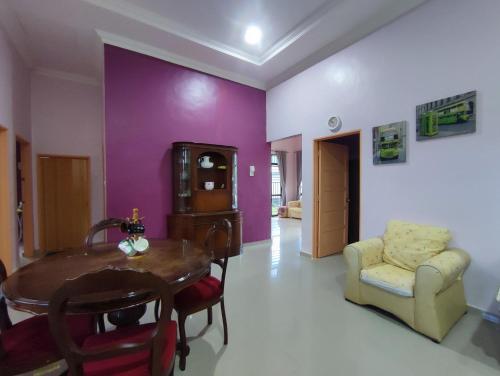 a dining room with purple walls and a table and chairs at NikNa Homestay Batu Rakit - WIFI in Kampong Ru Tujoh