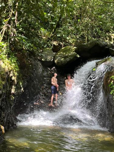 two men playing in a waterfall in the jungle at Sam's Bungalows And Treks in Bukit Lawang