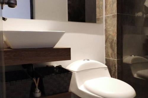 y baño con aseo blanco y lavamanos. en Apartamento Manizales Colombia en Manizales