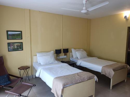 a hotel room with two beds and a chair at Chai Seeds Resort in Mākum